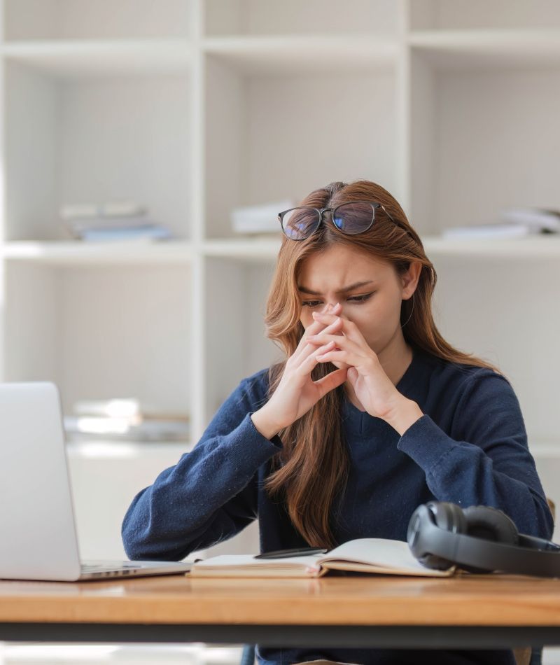 Chica que está estudiando y su cara refleja agobio y frustración.