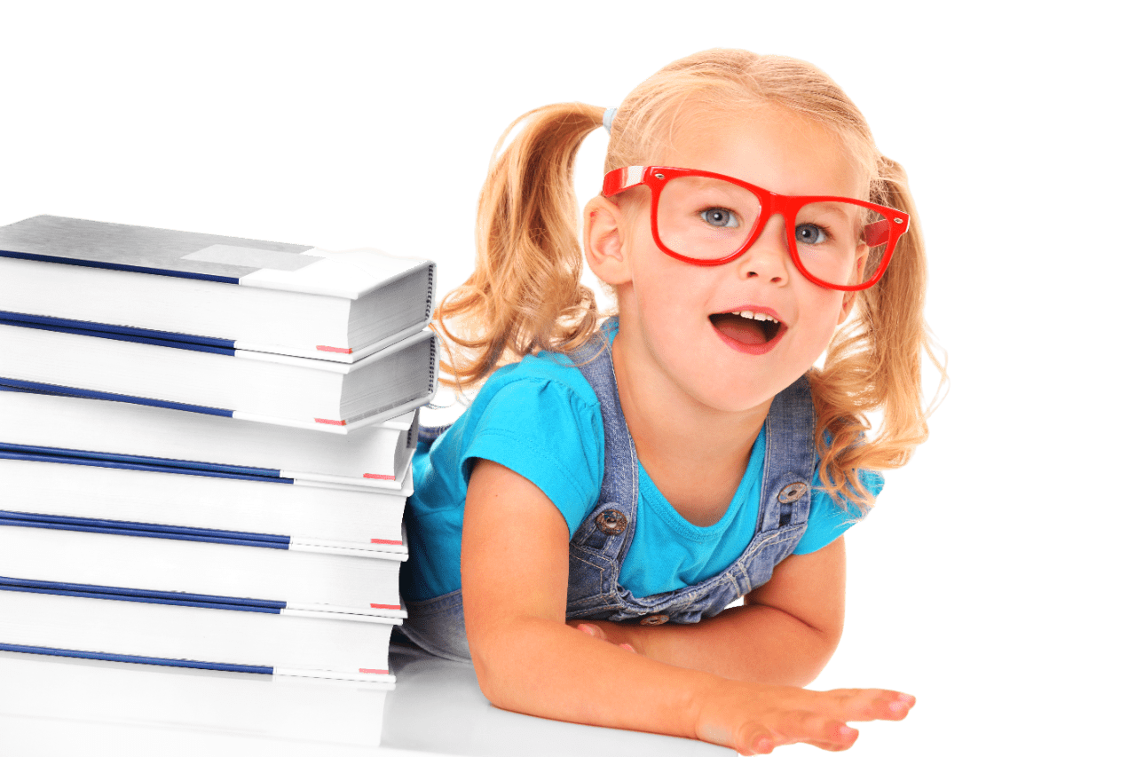 Una niña rubia con gafas de pasta roja que está tumbada con una pila de libros al lado.