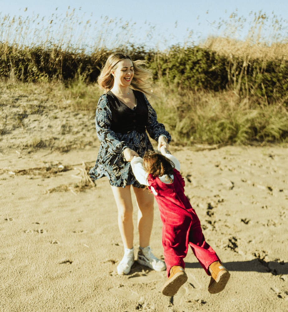Imagen de Ana Parro jugando con su hija en la playa.