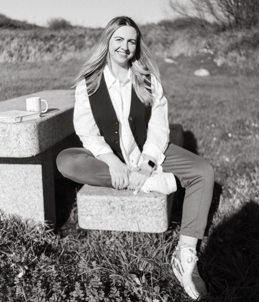 Foto en blanco y negro de Ana sentada en un banco de piedra en el campo.
