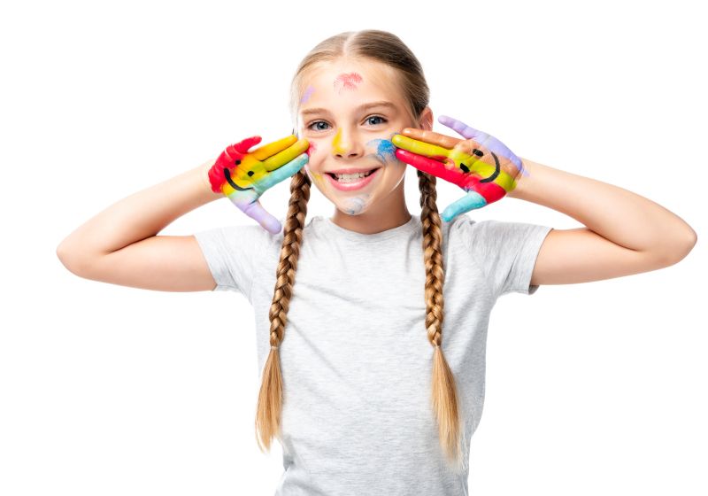 Niña feliz con las manos pintadas con una cara feliz.